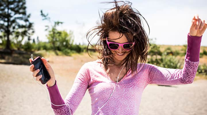 Woman with a boost of energy from supplements listening to music and dancing outdoors