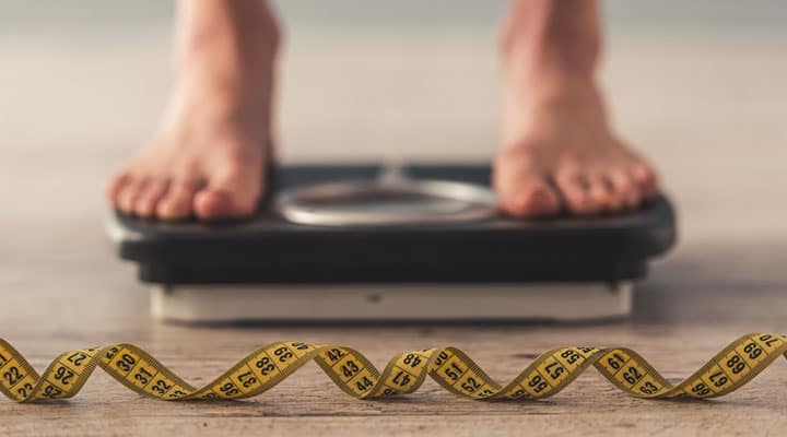 Man on scale to check body weight and body fat