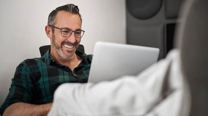 Man on a couch looking at a computer boosts learning with lutein and zeaxanthinon