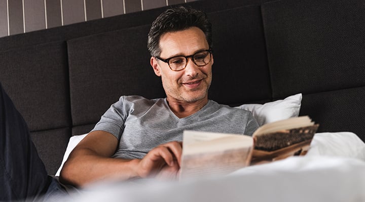 Man reading a book before bedtime to avoid looking at a screen