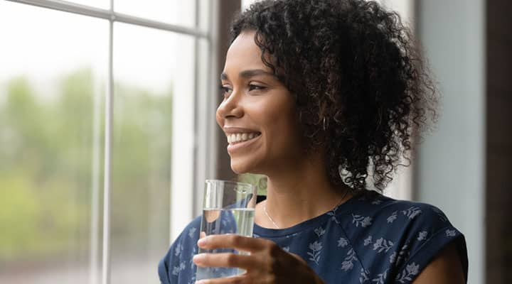 Woman with healthy blood sugar levels from ashwagandha standing with a glass of water