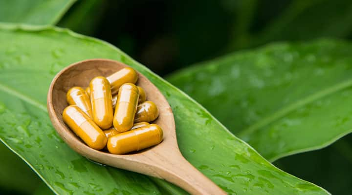 Quality curcumin supplement in capsules on a spoon