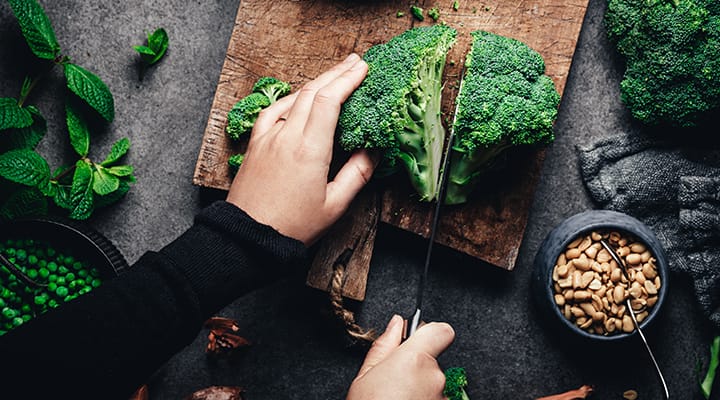 Woman halving head of broccoli as a part of a vegetarian or vegan plant-based diet