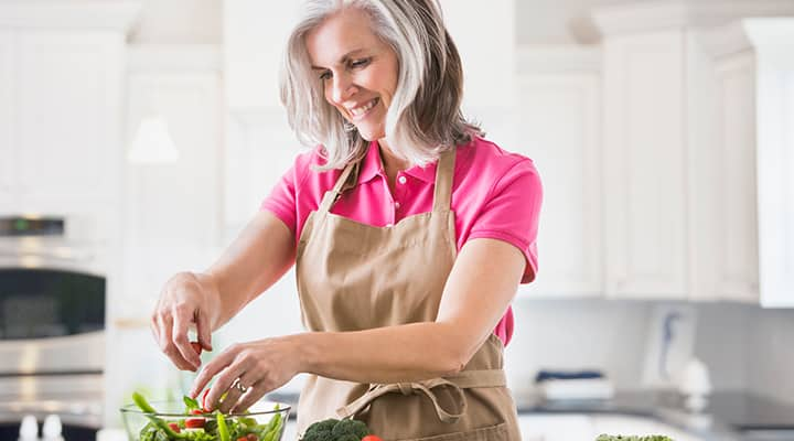 Woman making salad with cruciferous vegetables for nutrition to lower Alzheimer's risk