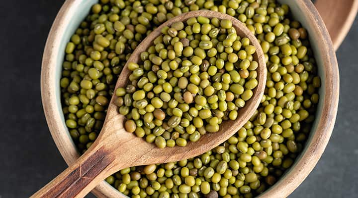 Spooning mung beans from a wooden bowl