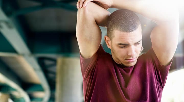 Fit young man stretching under a bridge