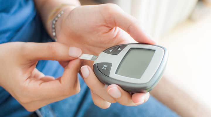 Woman preparing to test glucose with handheld device