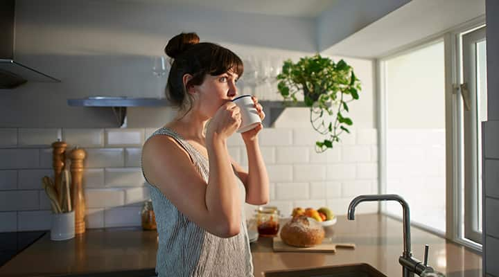 Woman enjoying morning coffee in her kitchen