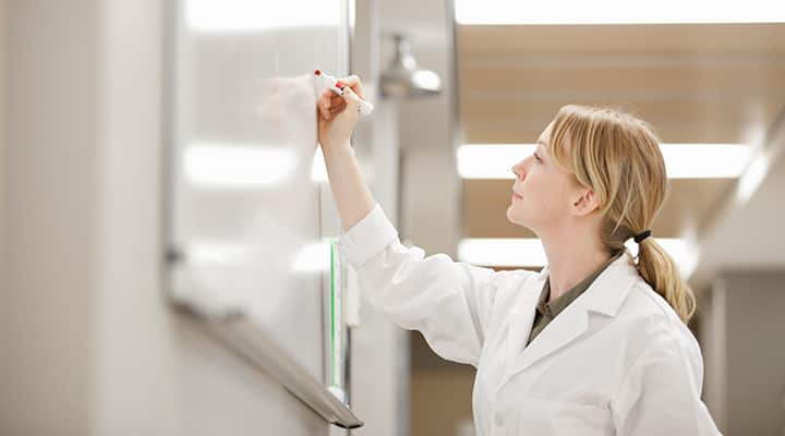 Researcher making notes on laboratory whiteboard