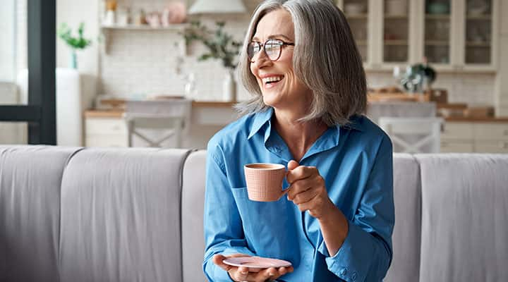 Woman laughing while enjoying cup of coffee