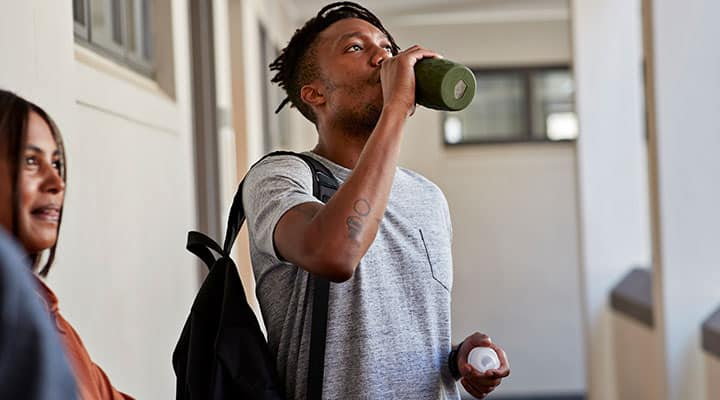 Man taking a sip from a water bottle with BCAAs